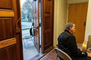 A photo depicts Governor Dan McKee sitting in the Pembroke field house, two teenagers visible through an open door behind his turned back.

