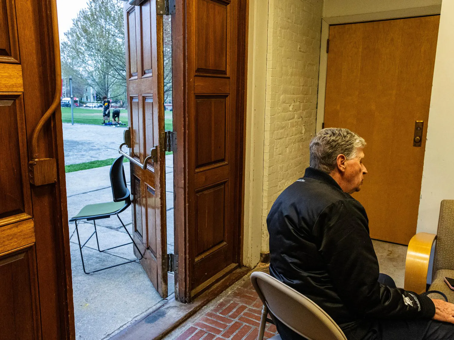 A photo depicts Governor Dan McKee sitting in the Pembroke field house, two teenagers visible through an open door behind his turned back.