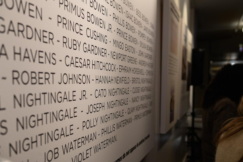 A photo showing a close-up of a vertical panel with names listed as visitors walk past. 