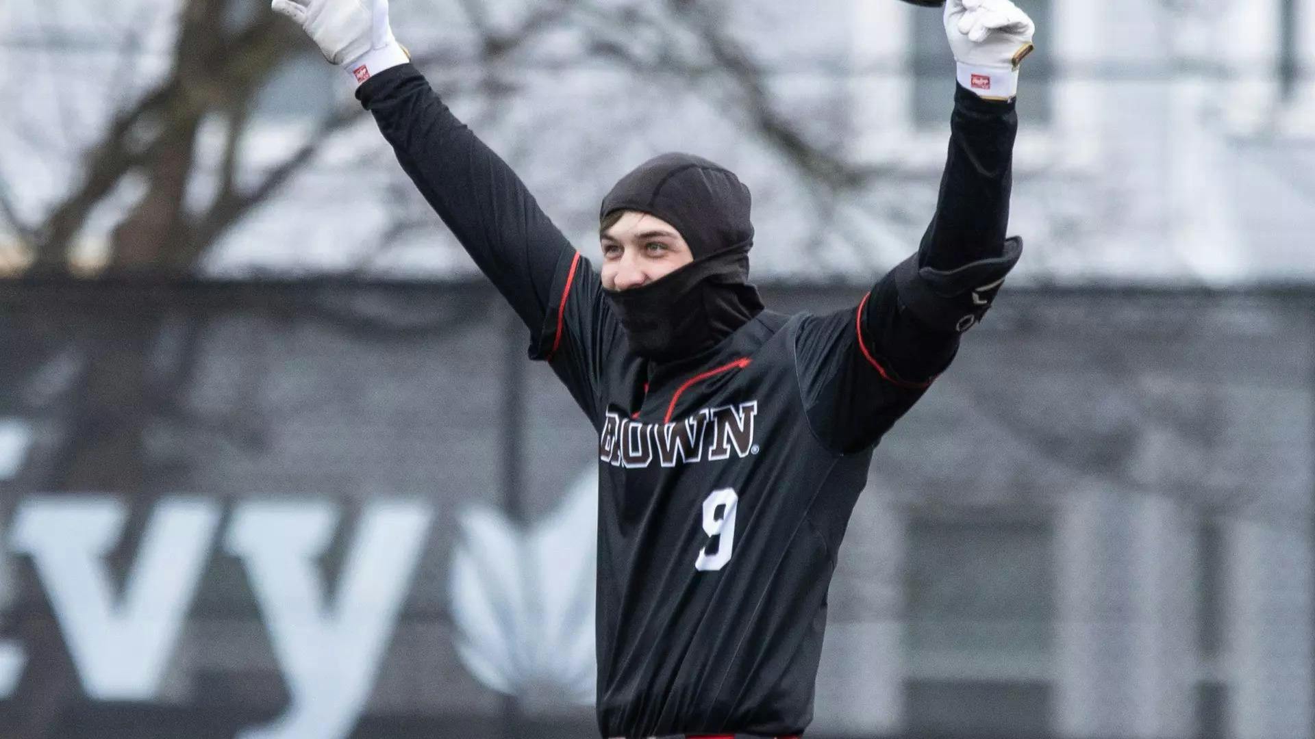 A picture of Logan Meusy celebrating after hitting the grounder to left field that drove in Christian Butera for the game-winning run. Meusy is wearing a black baseball uniform and a balaclava.