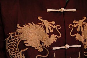 Photo of a red traditional Chinese shirt with traditional Chinese knot buttons and a pair of dragons embroidered on it.

