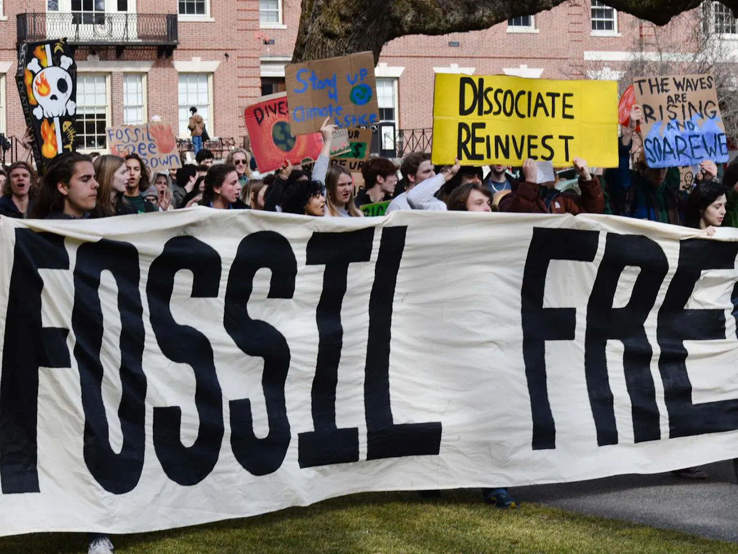 Students protest on the main green holding a large sign reading "Fossil Free Brown."