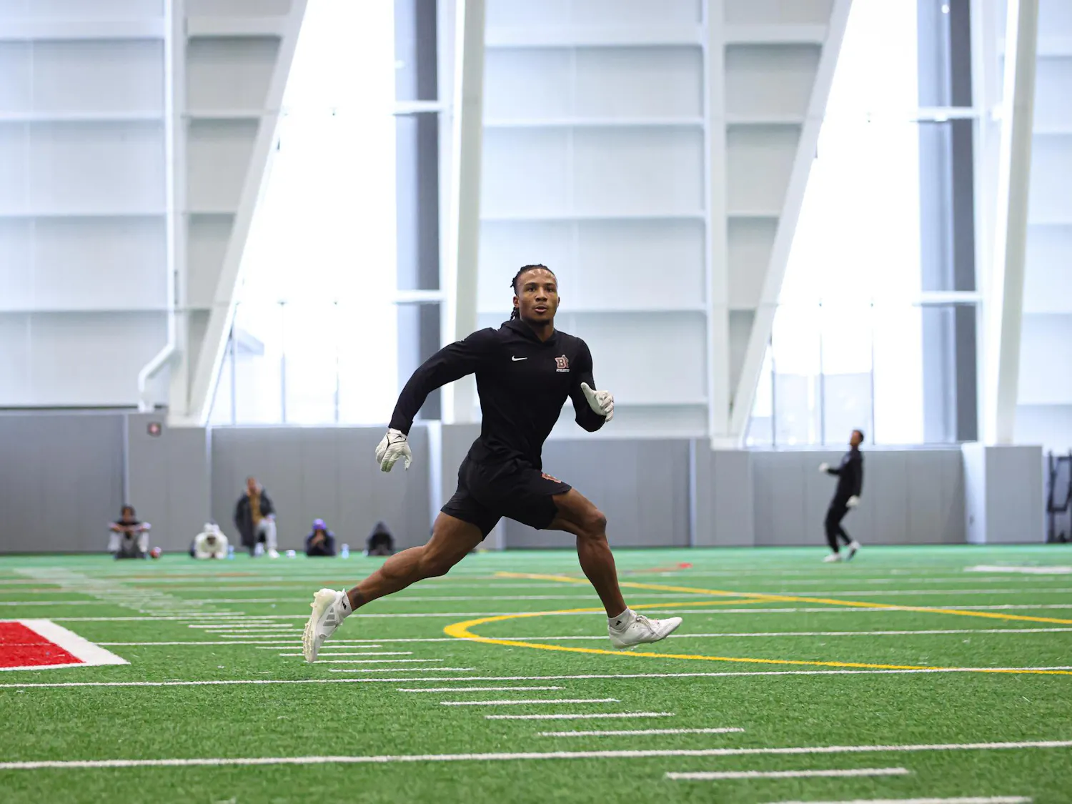 A man runs across a turf field.