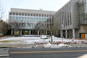 An outside shot of snowy Barus and Holley with flowers lining the street as part of the memorial for Ella Cook '28 and Mukhammad Aziz Umurzokov '29