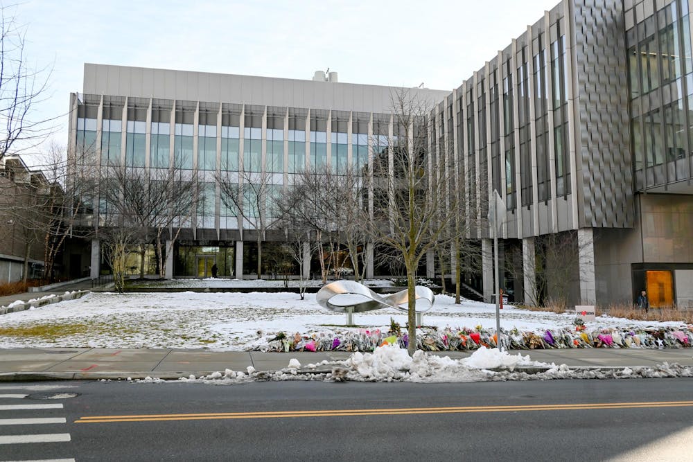 An outside shot of snowy Barus and Holley with flowers lining the street as part of the memorial for Ella Cook '28 and Mukhammad Aziz Umurzokov '29