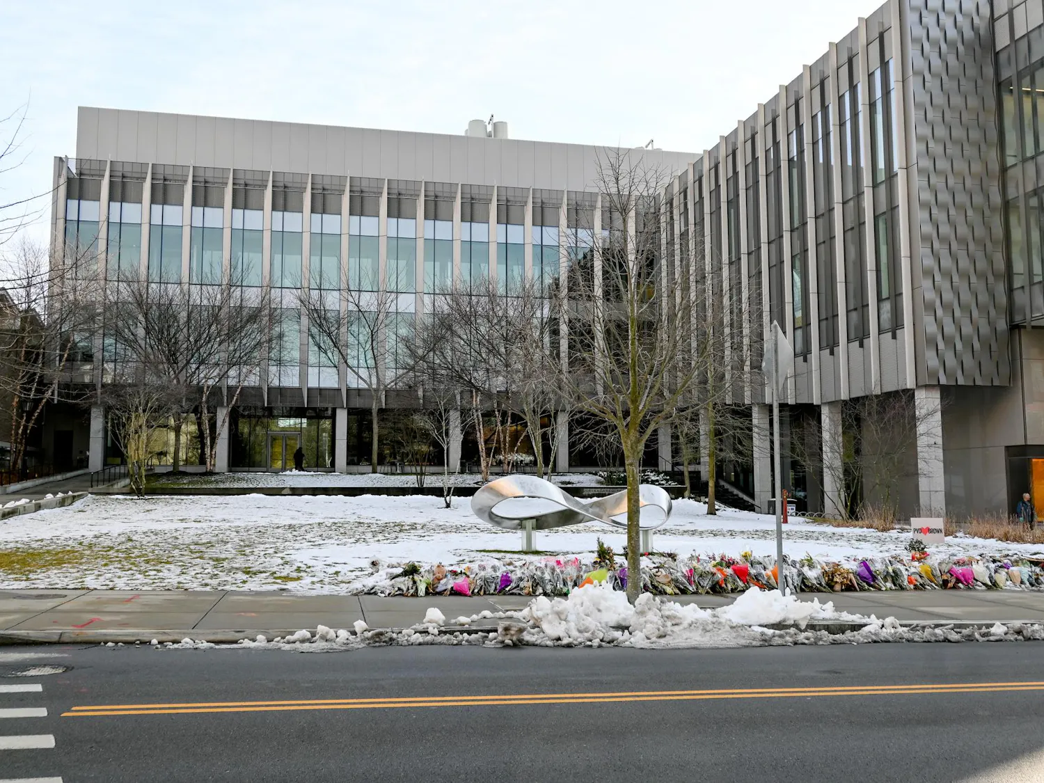 An outside shot of snowy Barus and Holley with flowers lining the street as part of the memorial for Ella Cook '28 and Mukhammad Aziz Umurzokov '29