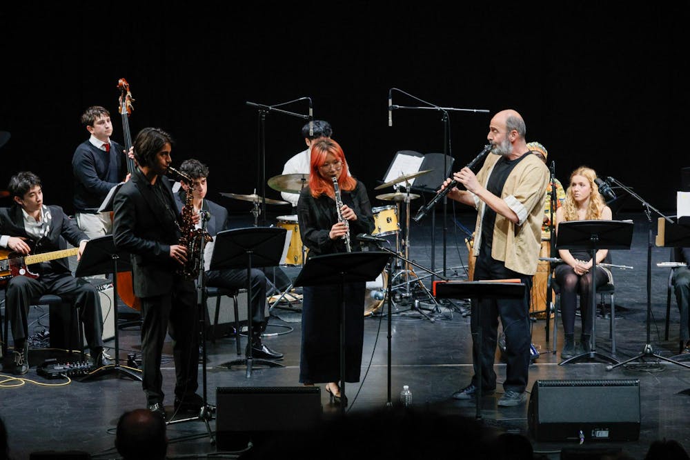 A photograph of an orchestra on stage. The photo centers three main performers.