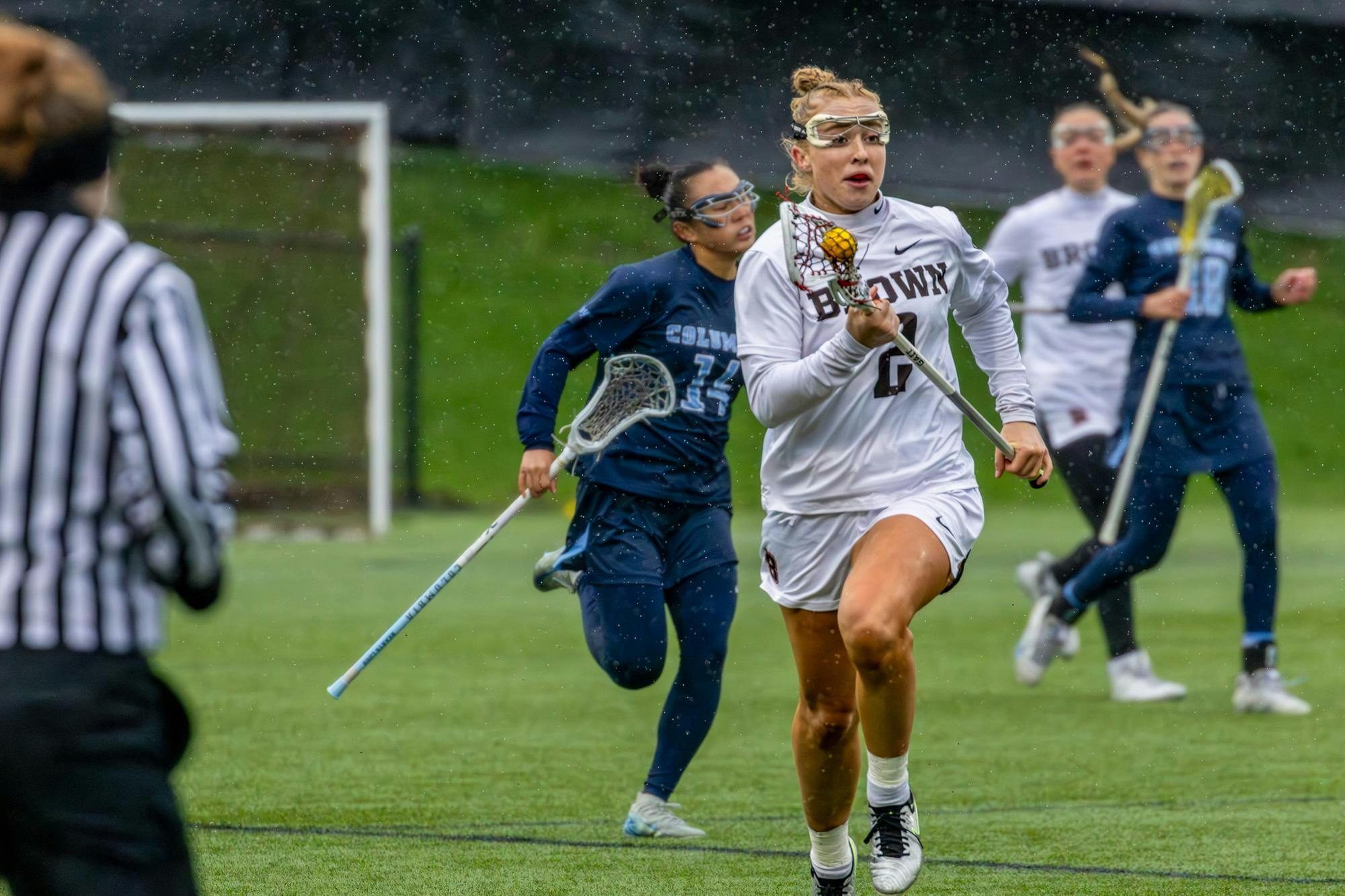 Riley Peterson is running with the ball in her crosse, Columbia defenders are chasing her in the background.