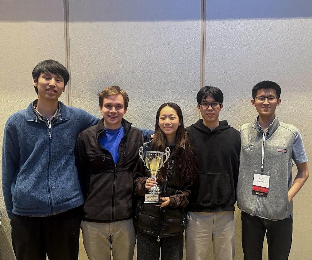 A photo of five students with the middle individual holding a trophy. 