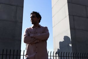 A photo of Mahajan crossing him arms, with two pillars to the side of him, and a shadow casting over his face.