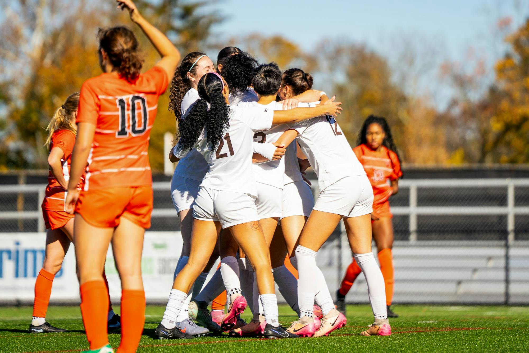 Photo of a group of soccer players huddling on a soccer field. 