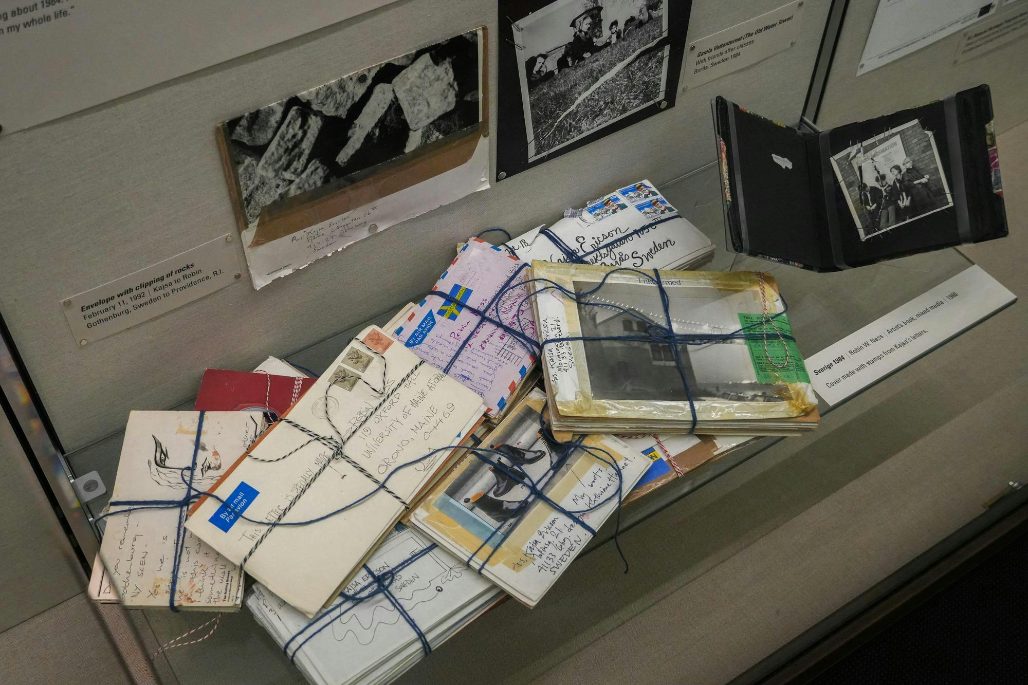 Photo of a pile of letters, with clusters tied together with blue and multicolored thread, in an exhibit shadowbox.