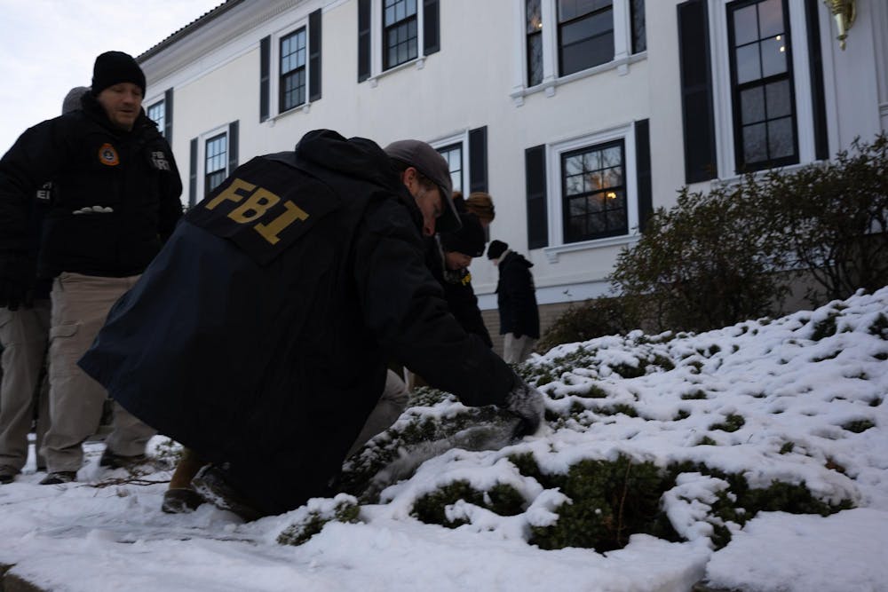 FBI agents dig through snowy bushes. 