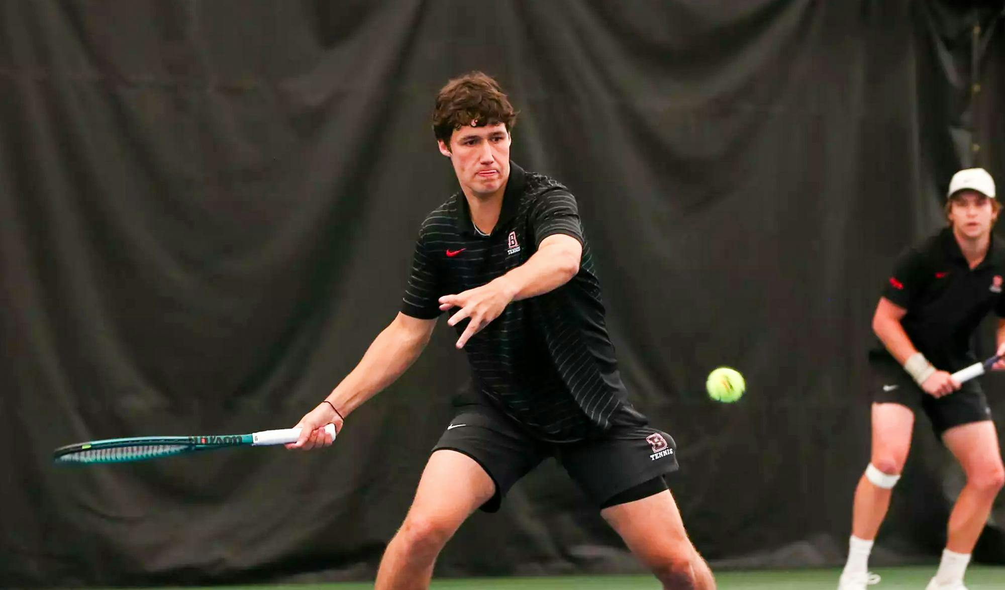 A tennis player preparing to swing his racket to hit an incoming tennis ball.  