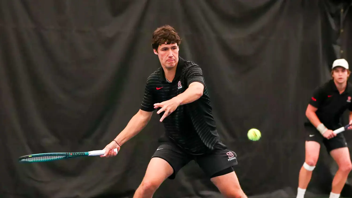 A tennis player preparing to swing his racket to hit an incoming tennis ball.
