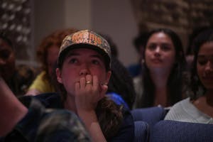 A student with a Harris-Walz hat looks into the distance