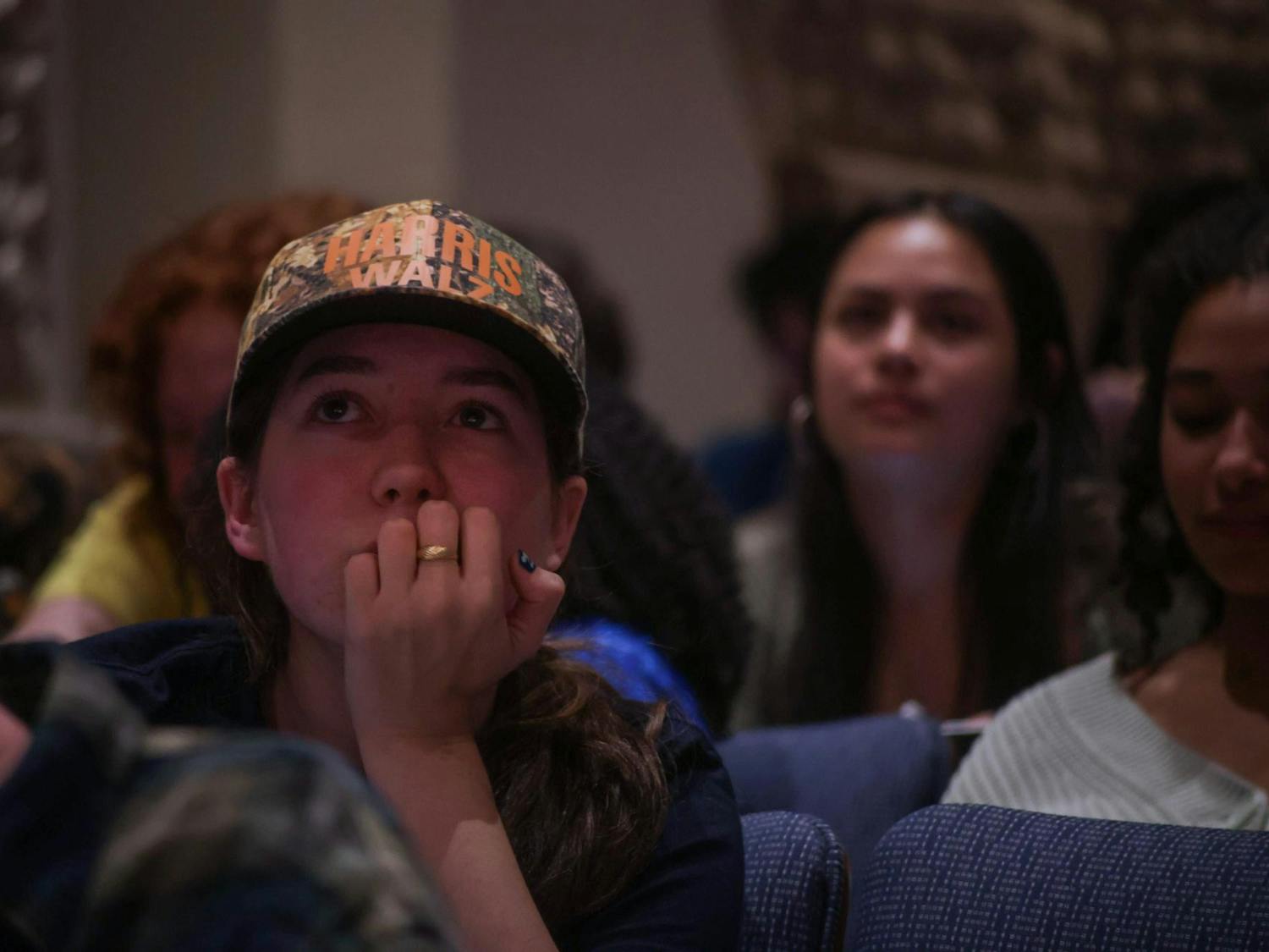 A student with a Harris-Walz hat looks into the distance
