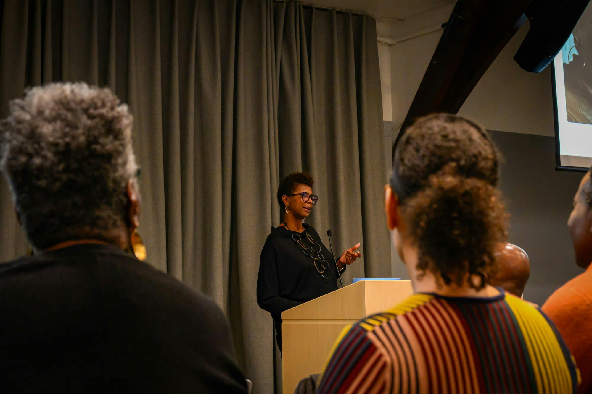 Photo of Dana Williams standing at a podium giving a lecture to an audience.