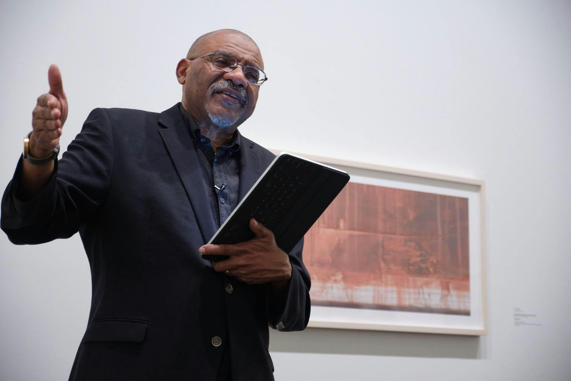 A picture of Kwame Dawes speaking while holding a tablet.