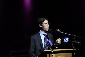 Mayor Brett Smiley speaking behind a wooden podium with microphones attached to it.