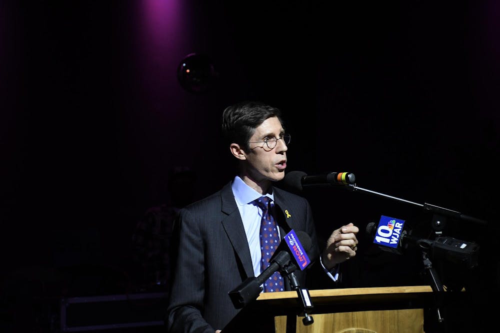Mayor Brett Smiley speaking behind a wooden podium with microphones attached to it.
