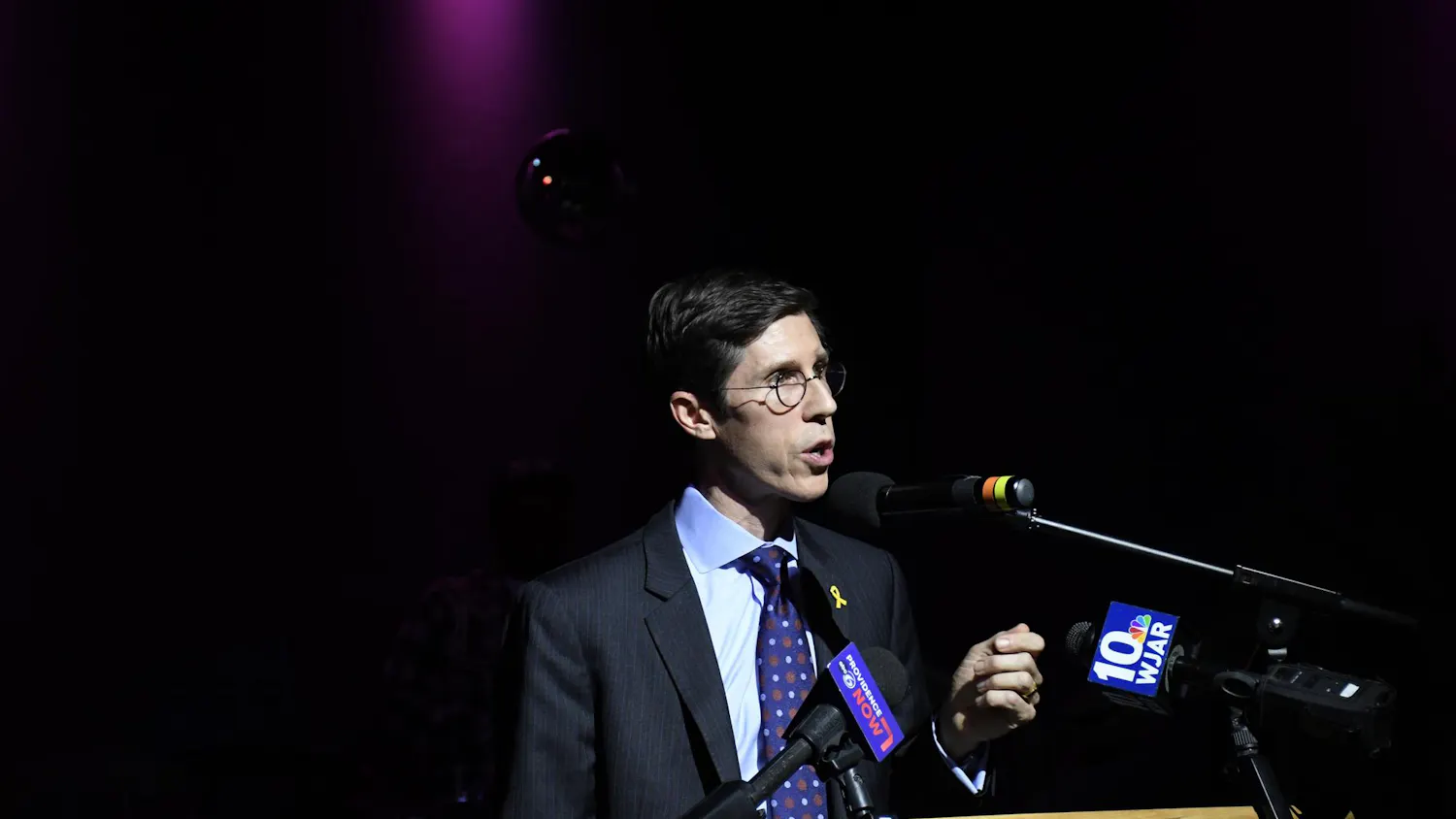 Mayor Brett Smiley speaking behind a wooden podium with microphones attached to it.
