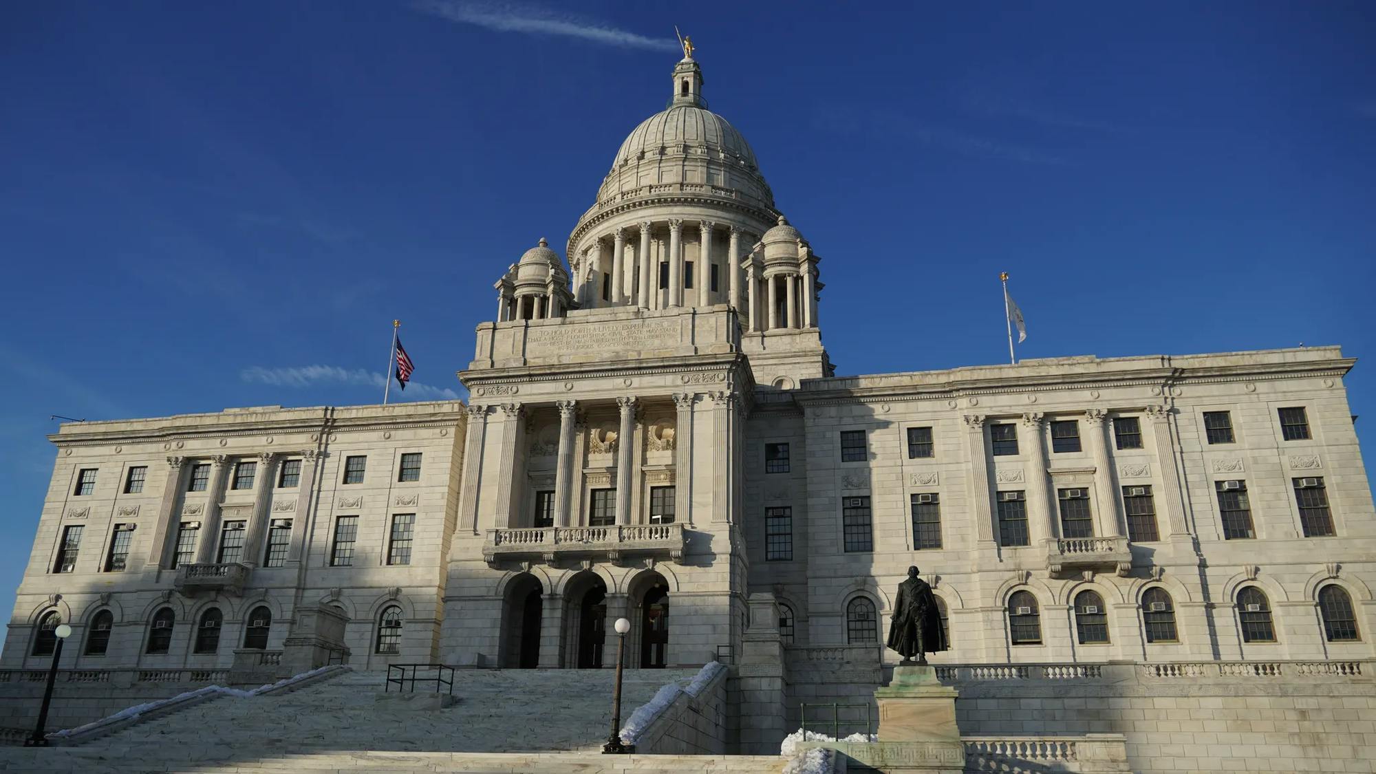 A daytime photo of the Rhode Island State house with a deep blue sky in the background. 