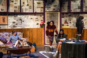 A stage with three actors talking.