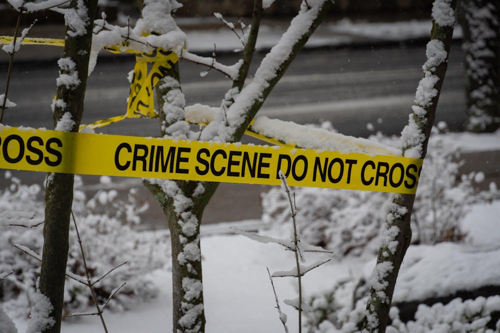 Crime scene tape wrapped around branches of a snow-covered tree. 
