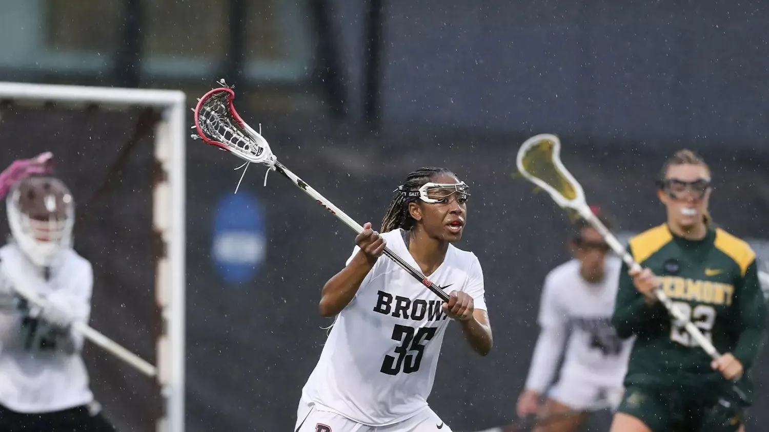 A photo of a women’s lacrosse player in the rain.