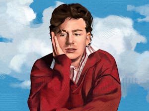 Charlie Puth, wearing a red shirt, leans with a hand on his cheek against a background of the sky. 