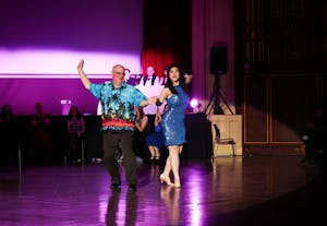A man in a Hawaiian shirt dances with a girl in a sparkly blue dress.