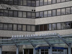 A sign that says "Rhode Island Hospital" on the front awning of a large tan brick building.