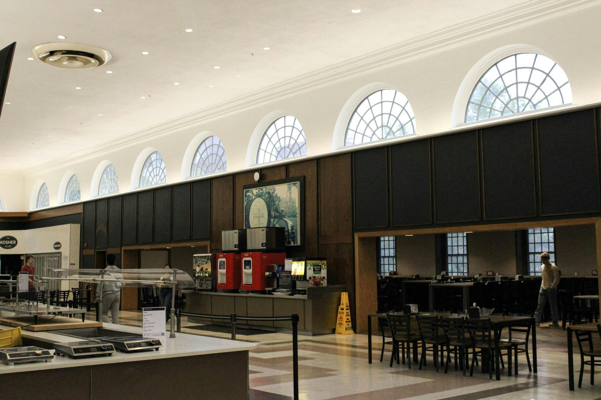 A photo showing the inside of the Sharpe Refectory almost empty, facing drink machines and dining tables. 
