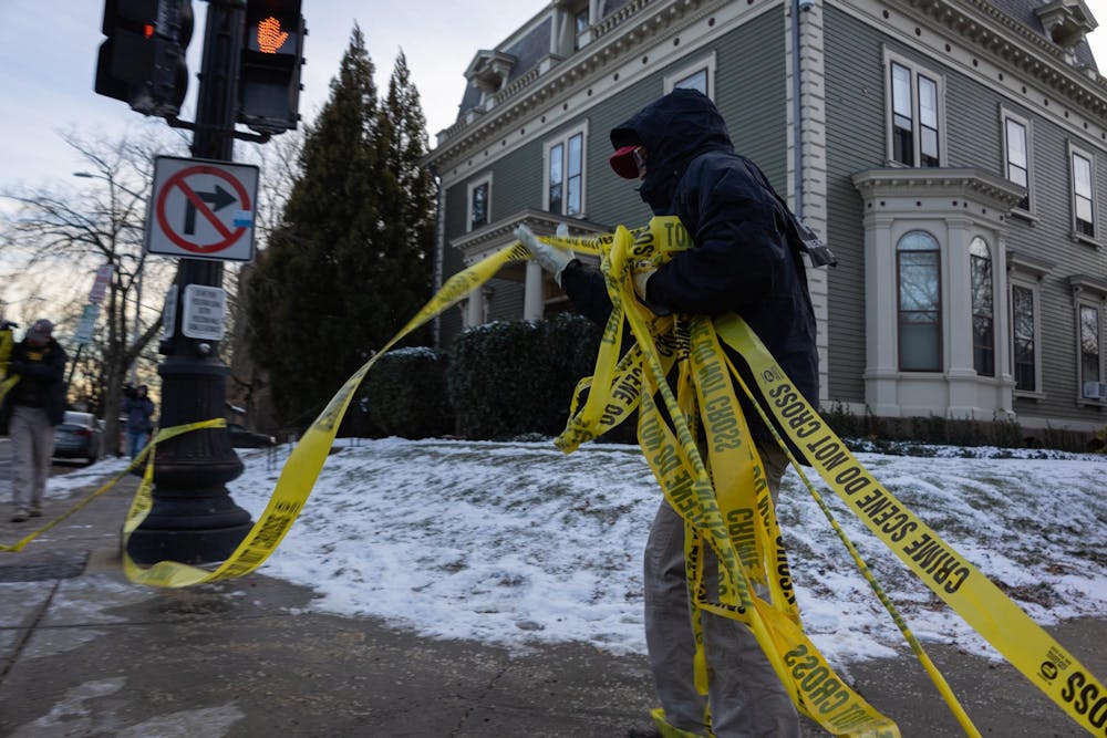 A photo shows an officer rolling up yellow police tape. 


