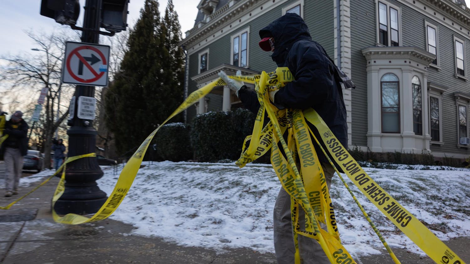 A photo shows an officer rolling up yellow police tape.