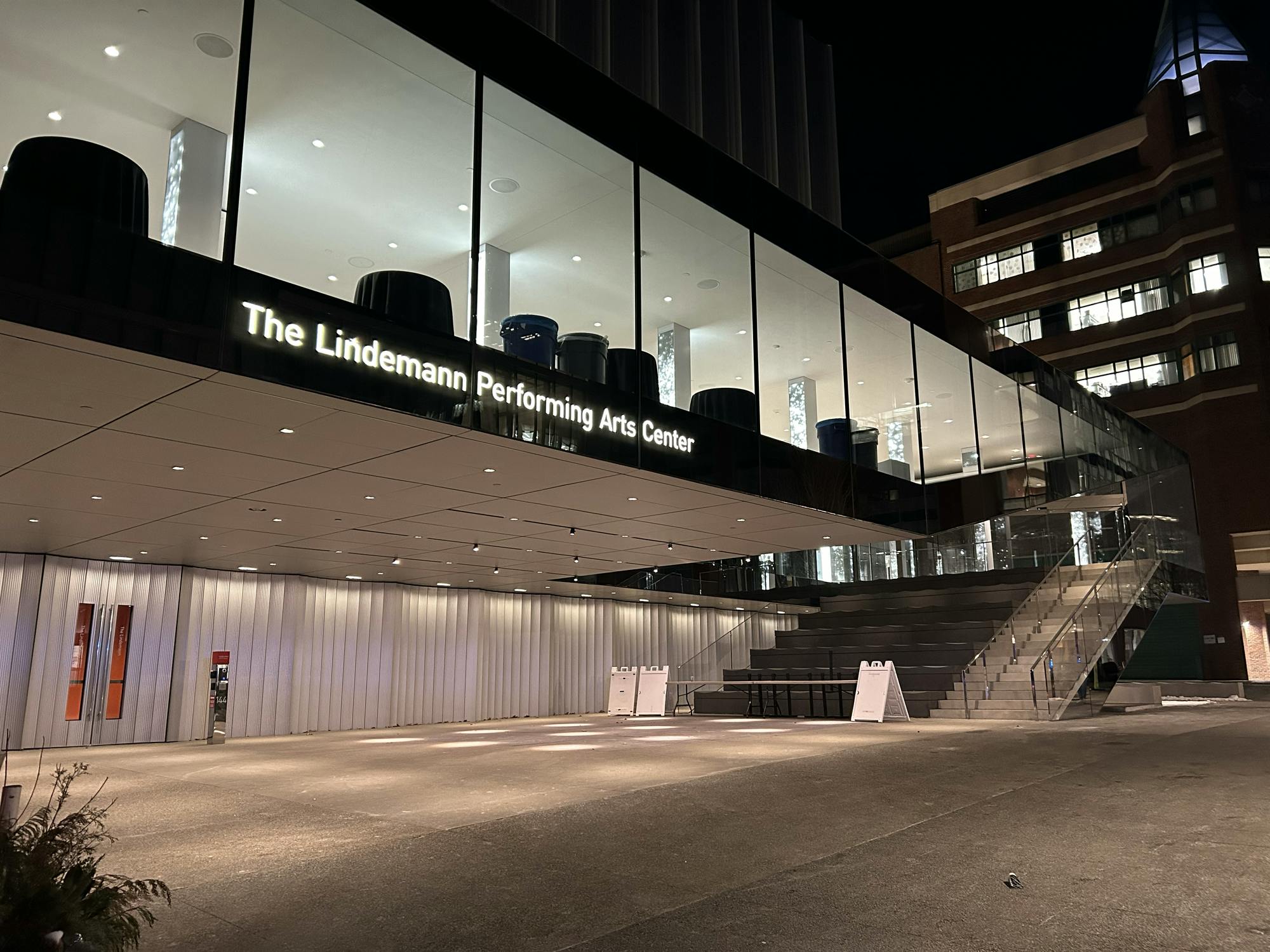 A photo of the Lindemann Performing Arts Center during the night, a glass-like building that faces out to the street. 