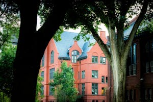 Photo of a red brick building in between two large trees.

