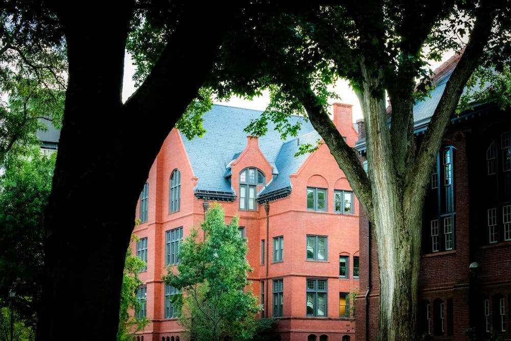 Photo of a red brick building in between two large trees.

