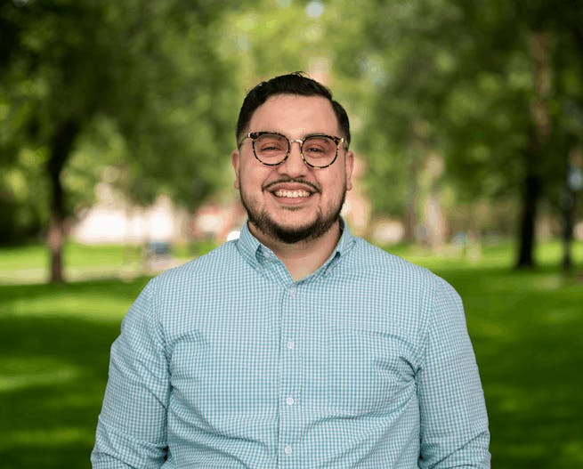 Robert Rosales, an assistant professor of behavioral and social sciences at the School of Public Health, poses for a headshot in a green-checkered button up shirt.