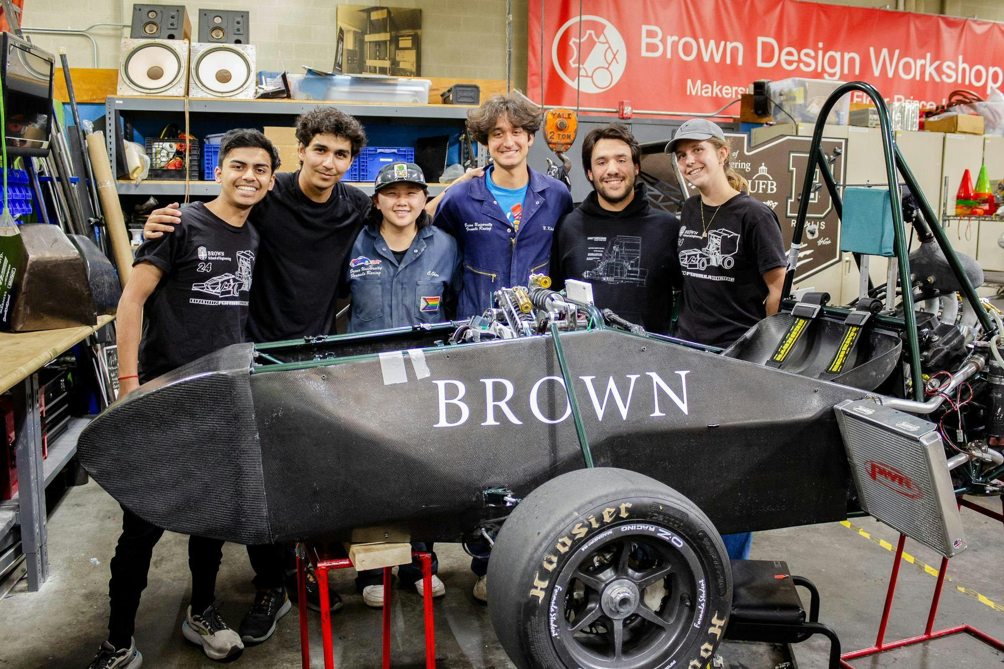Six Brown Formula Racing members stand behind their to-be finished car in the Brown Design Workshop.