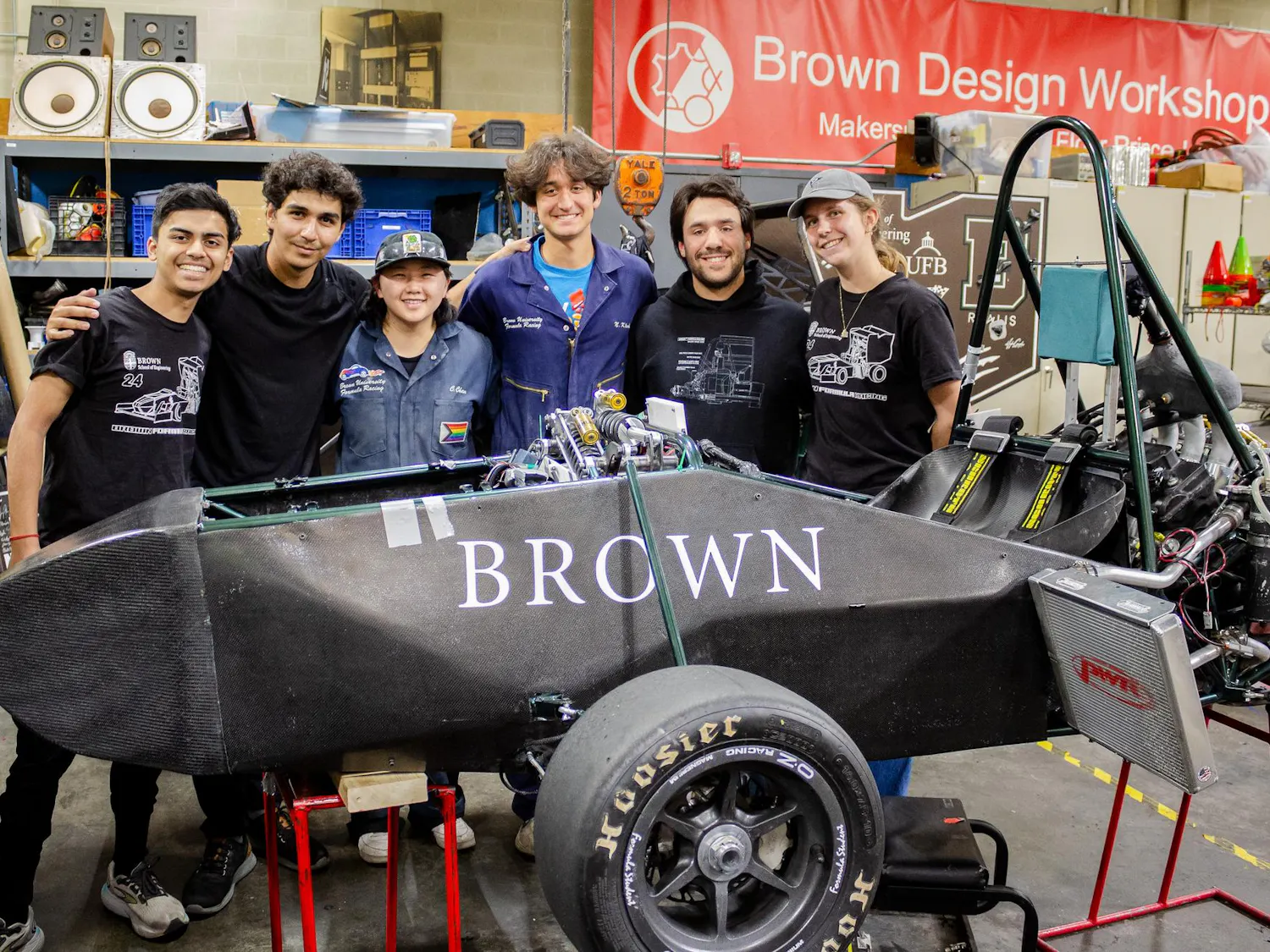 Six Brown Formula Racing members stand behind their to-be finished car in the Brown Design Workshop.