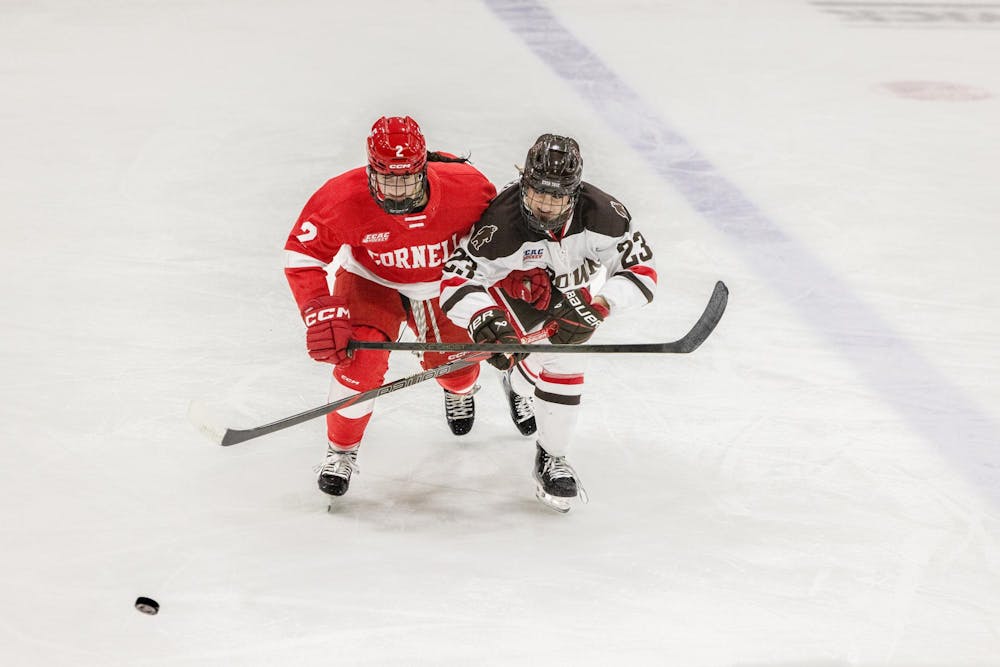 Two hockey players race for puck.