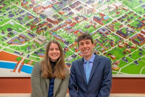 A photo of admissions officers Emily Wagg ’24 and Aidan Berman ’25 in front of a cartoon map of Brown University.