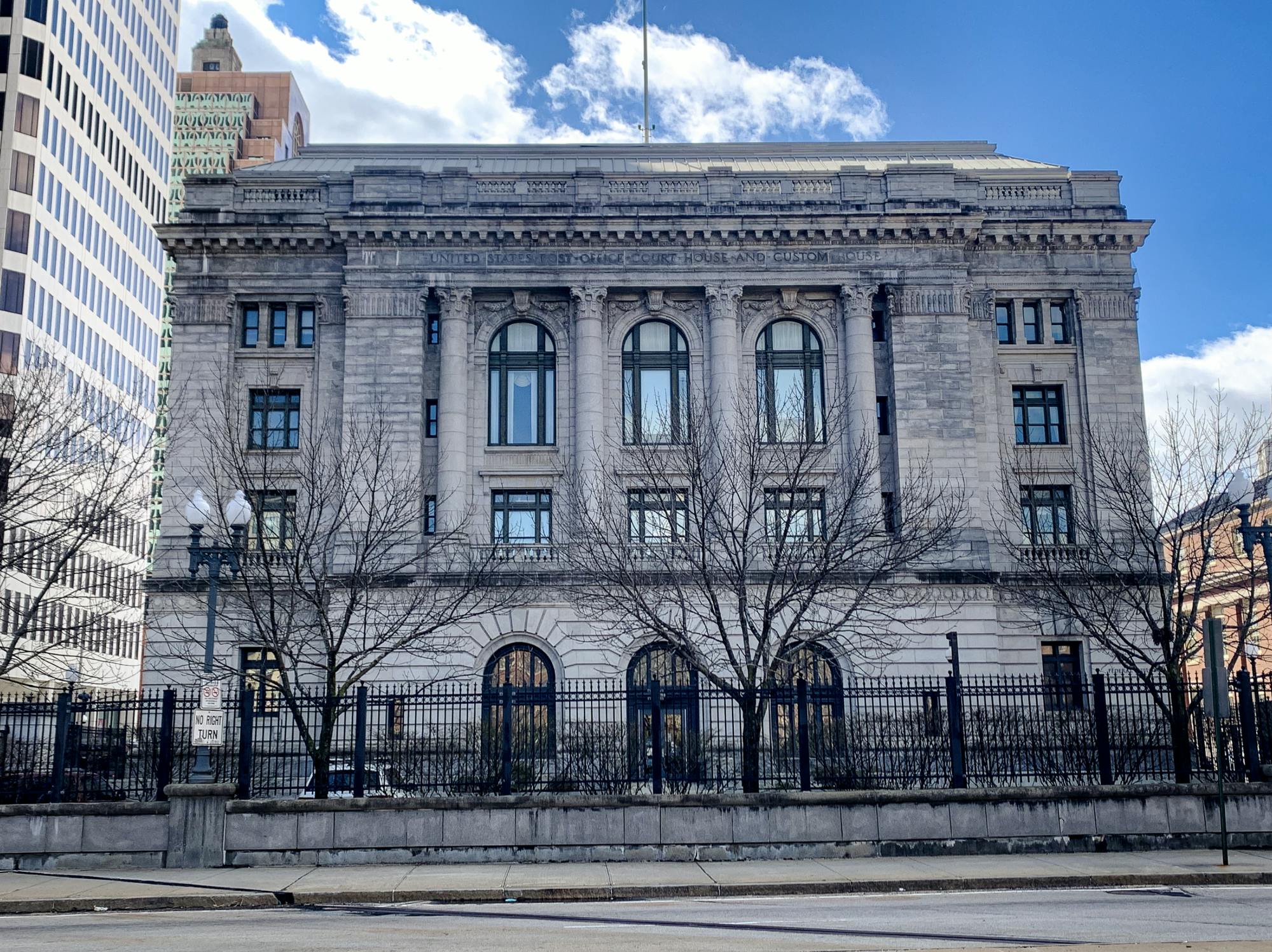 A large pale gray stone building with large windows and columns.