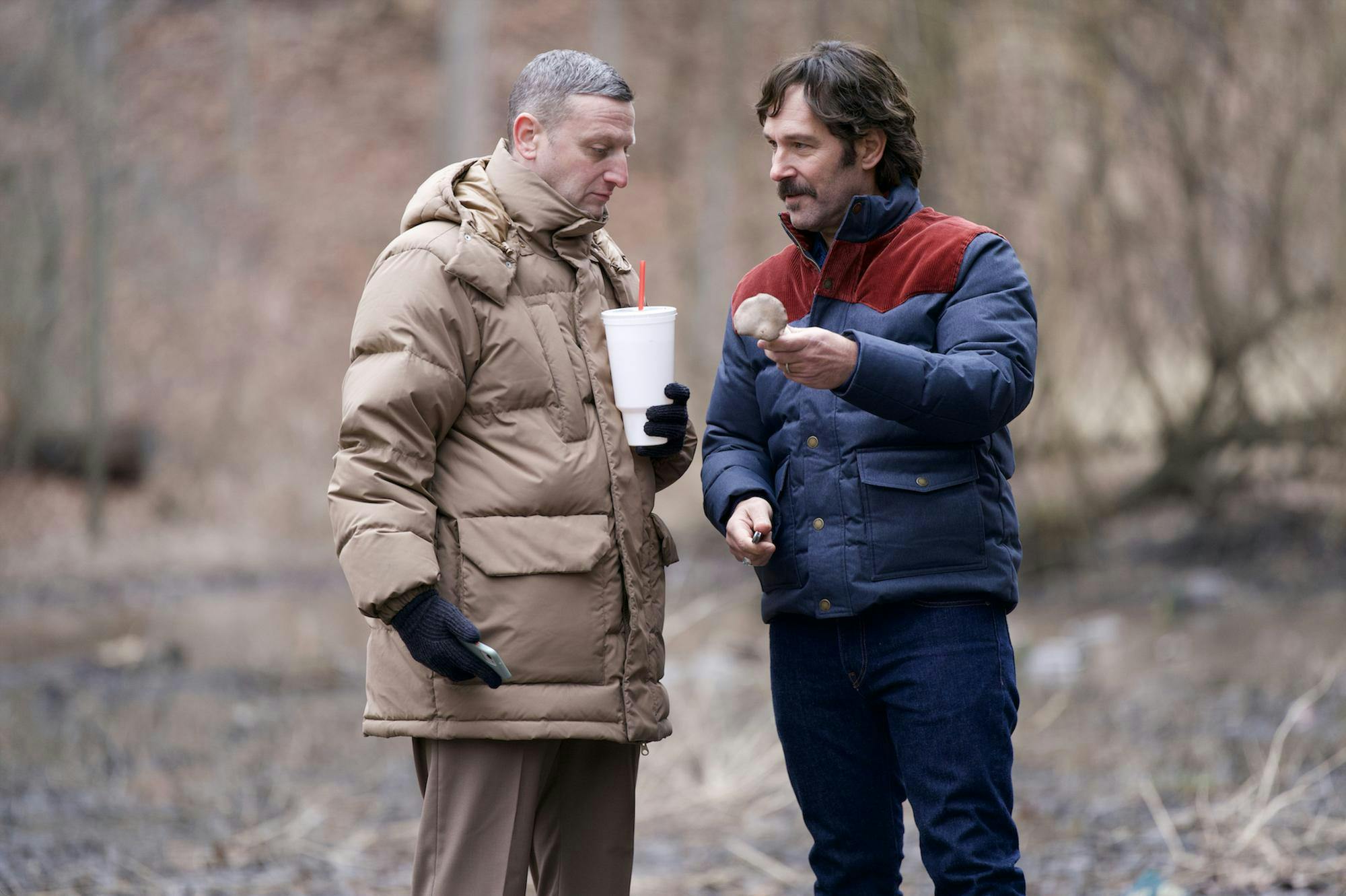 An image of Tim Robinson on the left and Pedro Pascal on the right, talking to each other in the woods.