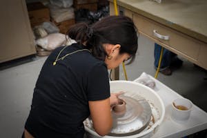 Photo of a student molding a ceramic piece on a pottery wheel.