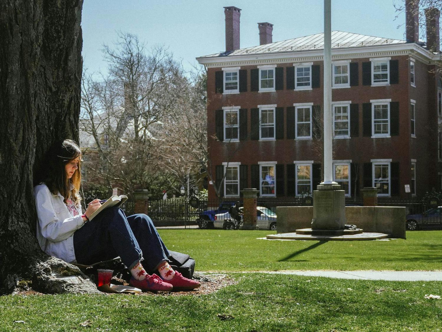 A photo of a girl reading a book on the Main Green.