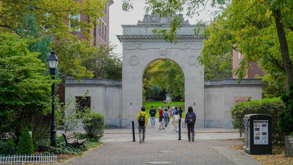 Photo of the Soldiers' Arch with green trees surrounding it and students walking through it