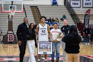 Lewis stands on the basketball court with his mother, father, and sister with him. He is holding a plaque with a picture of him during a game.